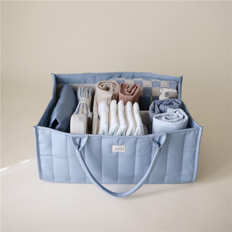 Mushie Baby Diaper Caddy in Tradewinds color, organized with diapers and newborn essentials in a soft blue fabric.