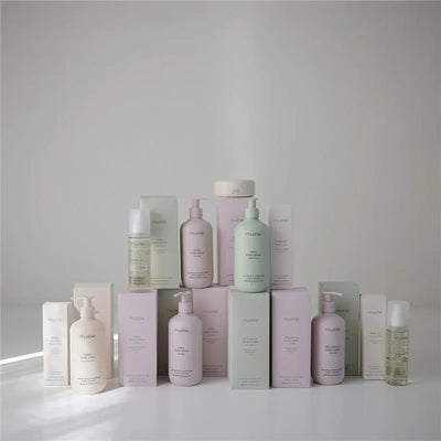 Mushie Baby Lotion and other skincare products displayed in various pastel-colored bottles and boxes on a white background.
