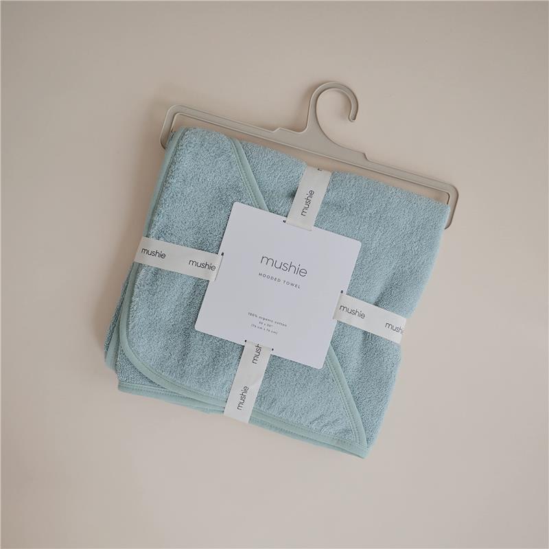 Organic cotton hooded towel in sea mist color, packaged and labeled with “mushie” brand details.