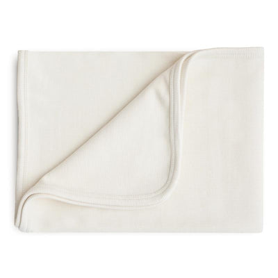 Mushie Extra Soft Baby Blanket in ivory color, featuring a smooth fabric with a folded corner showcasing its soft texture.