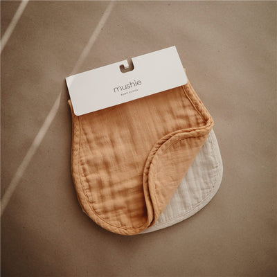 Mushie Organic Cotton Muslin Burp Cloths 2-Pack in fall yellow and fog, packaged with a white header card.