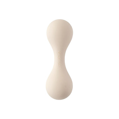 Mushie silicone baby rattle toy in shifting sand color, featuring an ergonomic design for easy gripping.