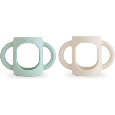 Silicone bottle handles in Cambridge Blue and Shifting Sand, designed to assist children in holding bottles.
