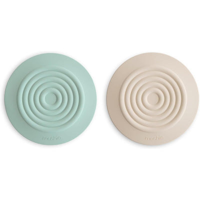 Mushie Silicone Drain Stopper 2-Pack in Cambridge Blue and Shifting Sand, featuring concentric circular designs.