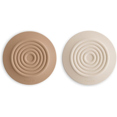 Silicone drain stoppers in natural and shifting sand colors, featuring concentric circular designs.