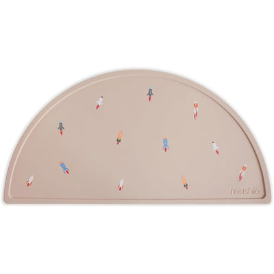 Mushie Silicone Placemat in beige with colorful rocket ship designs, ideal for mealtime or playtime.