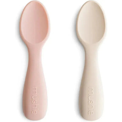 Silicone toddler starter spoons in blush and shifting sand colors, featuring a rounded design and soft grip.