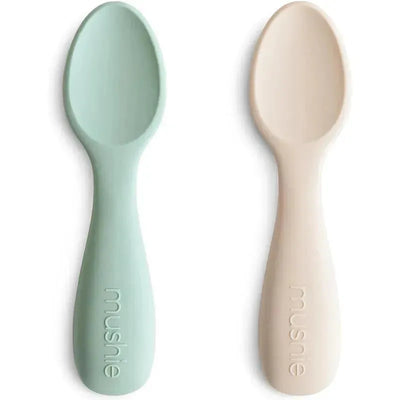Silicone toddler starter spoons in Cambridge Blue and Shifting Sand colors, featuring a comfortable grip for easy feeding.