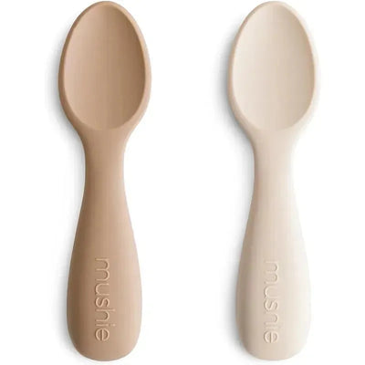 Silicone toddler starter spoons in natural and shifting sand colors, featuring rounded edges and ergonomic handles.
