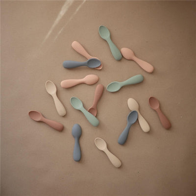 Silicone toddler starter spoons in natural and shifting sand colors, featuring a soft, child-friendly design.