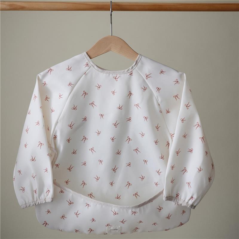 Long sleeve baby bib in white with pink bow patterns, water-resistant and adjustable fit for easy use.