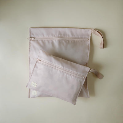 Water-resistant wet bags in blush color, featuring two sizes with zippers and stitched labels.