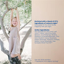 Organic micellar water bottle with olive oil and aloe, featuring a smiling girl perched on an olive tree.