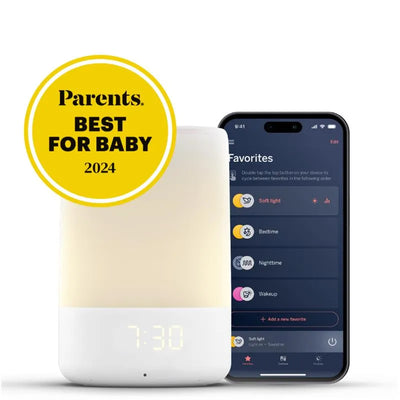 Nanit Sound and Light Smart Baby Night Light with a digital clock showing 7:30, paired with a smartphone displaying app features.