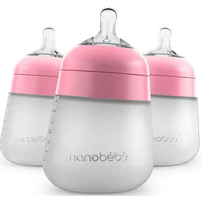 Three Nanobebe 9oz silicone baby bottles in pink, featuring a soft grip and a wide base design for stability.