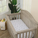 Nursery crib featuring a grey wooden frame and a mattress with a Lion King-themed sheet, decorated with playful animal sketches.
