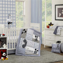 Mickey Mouse-themed nursery with blue and white decor, featuring a mobile, quilted blanket, and plush toys.