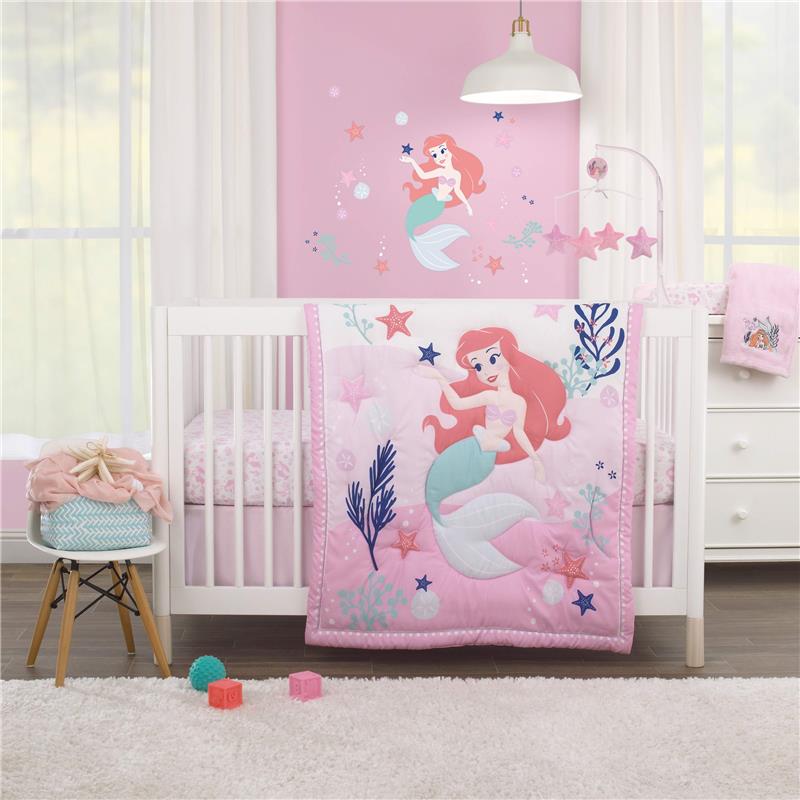 Nojo Disney The Little Mermaid Musical Mobile in a nursery with a pink quilt featuring Ariel and decorative elements.