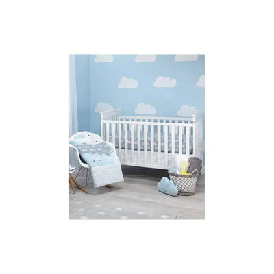 Nojo Little Love Happy Little Clouds Plush Pillow rests on a cozy nursery chair, surrounded by clouds and a crib.