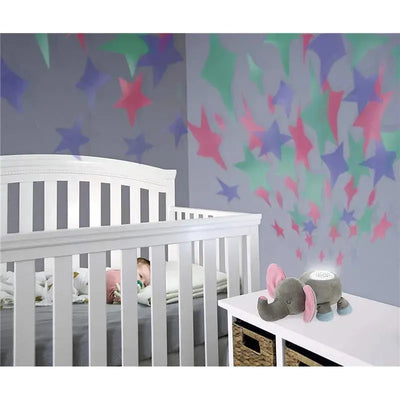 Plush elephant night light beside a crib with a sleeping baby, featuring colorful star projections on the wall.