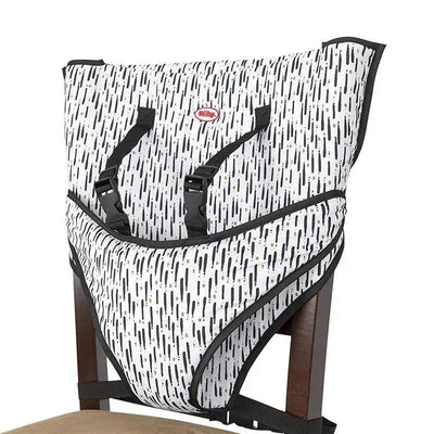 Portable travel chair designed by Nuby, featuring a child seat with adjustable straps and a white and black pattern.