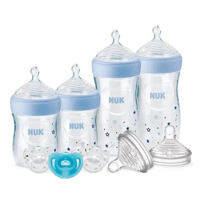 Simply Natural gift set by NUK featuring two clear baby bottles with blue caps, two pacifiers, and bottle lids.