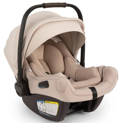 Nuna PIPA™ aire Infant Car Seat in Biscotti color, featuring an adjustable canopy and a secure base with safety labels.
