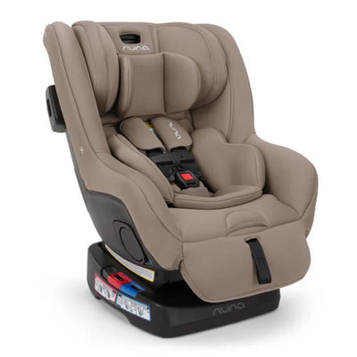 Nuna RAVA™ next Convertible Car Seat in Cedar color, featuring plush padding, adjustable harness, and safety labels.