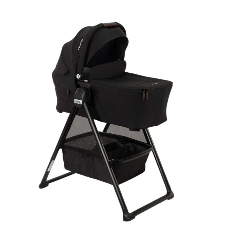 Nuna Swiv Stroller with a black bassinet attachment on a stand, featuring a storage basket underneath.