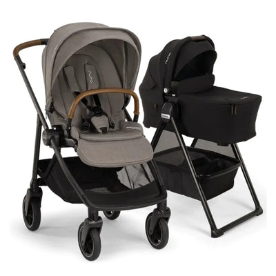 Nuna Swiv stroller with a gray seat and brown handle next to a black bassinet on a stand, showcasing its bundle design.