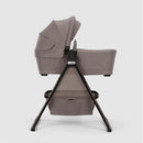 Nuna SWIV & TRIV Series Bassinet in Umber, featuring a soft fabric body and black stand, designed for infant comfort.