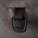 Close-up of the Nuna logo on a black buckle strap attached to gray fabric, part of the Nuna Trvl 360 Compact Stroller.