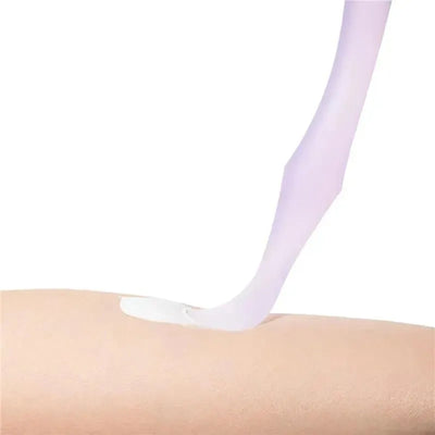 Diaper rash cream applicator with suction base dispensing cream onto a human arm. Colorful and ergonomic design visible.
