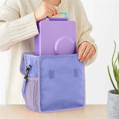 Omie insulated nylon lunch tote in purple, featuring a purple food container being placed inside.