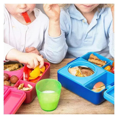 Children enjoying lunch with an OmieBox insulated bento box in blue and a pink container filled with various foods.