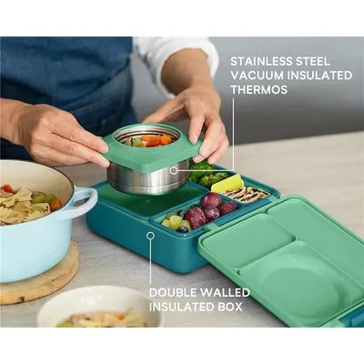 Insulated OmieBox in Meadow design with a stainless steel thermos and colorful food compartments; showing meal preparation.