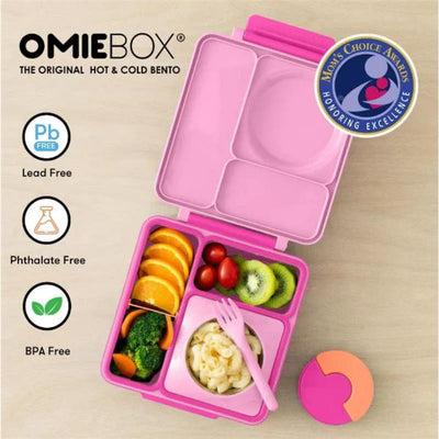 Insulated pink OMIEBox Bento lunch box with compartments for food, pasta, fruits, and a small container. BPA-free and lead-free labels visible.