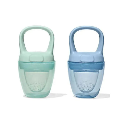 Two silicone self-feeders in opal green and dusk blue colors, designed for toddlers, featuring ergonomic handles and textured grips.