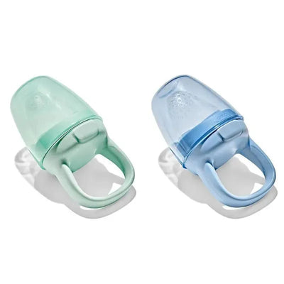 Two silicone self-feeders in opal green and dusk blue, designed for easy grip and safe food dispensing for infants.