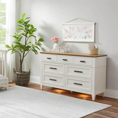 Parker House Artisan 7-drawer dresser in white with wooden top, featuring decorative items and a plant.