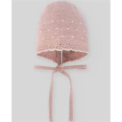 Knit newborn bonnet in powder pink and beige with decorative dots and ties for secure fit.