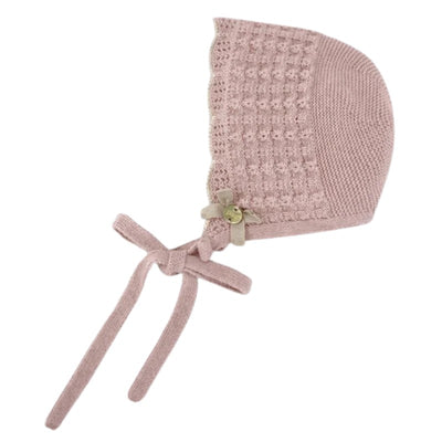 Knit newborn bonnet in cream and beige with a textured pattern and tie straps, adorned with a small floral decoration.