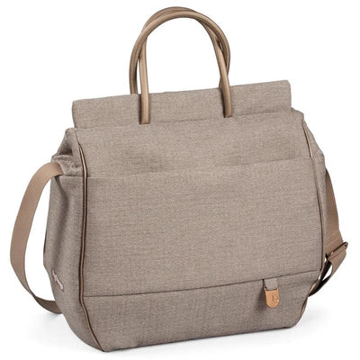 Diaper bag in beige fabric with two top handles and a shoulder strap, featuring a spacious design and side pockets.