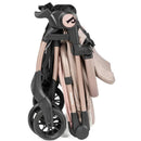 Peg Volo Compact Stroller in Mon Amour (Rose Gold), folded, showcasing its sleek design and compact wheels.
