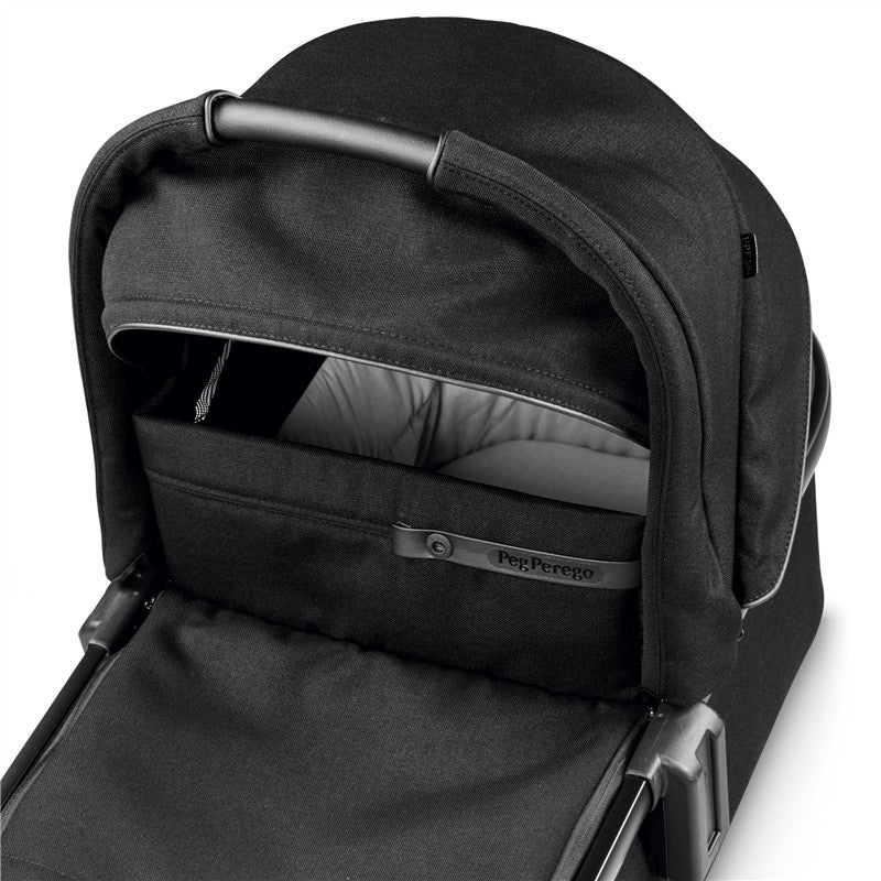 Peg Perego Ypsi Bassinet in True Black featuring a soft interior, adjustable canopy, and secure handle.