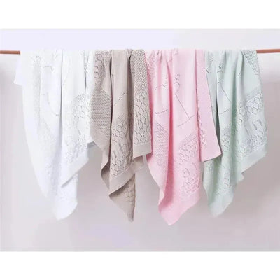 Pointelle design stroller blankets in white, beige, pink, and green, neatly arranged on a display.