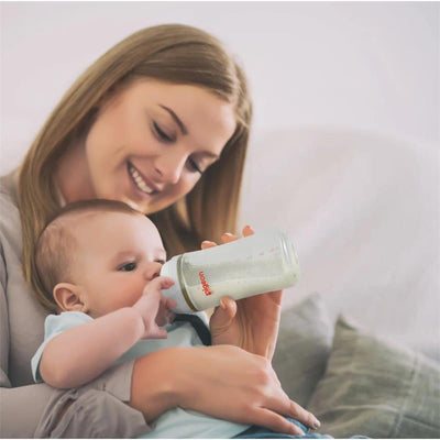 Mother feeding a baby with a Pigeon 4Pk PP Wide Neck Baby Bottle, 8.1 Oz, in a cozy indoor setting.