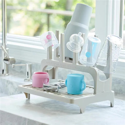Gray drying rack holding colorful cups and lids, showcasing its use for drying dishes efficiently.