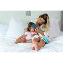 Mother applying Primo Passi baby cooling gel patch on child’s forehead while sitting on a bed.