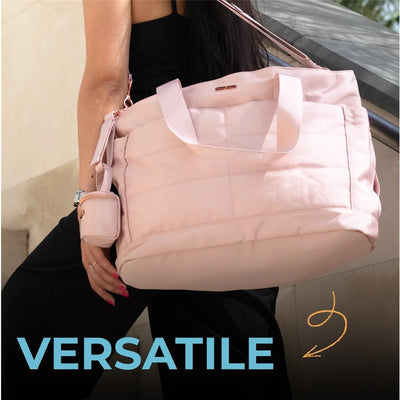 Pink Primo Passi Diaper Bag held by a person, featuring a zippered main compartment and a small side pocket.